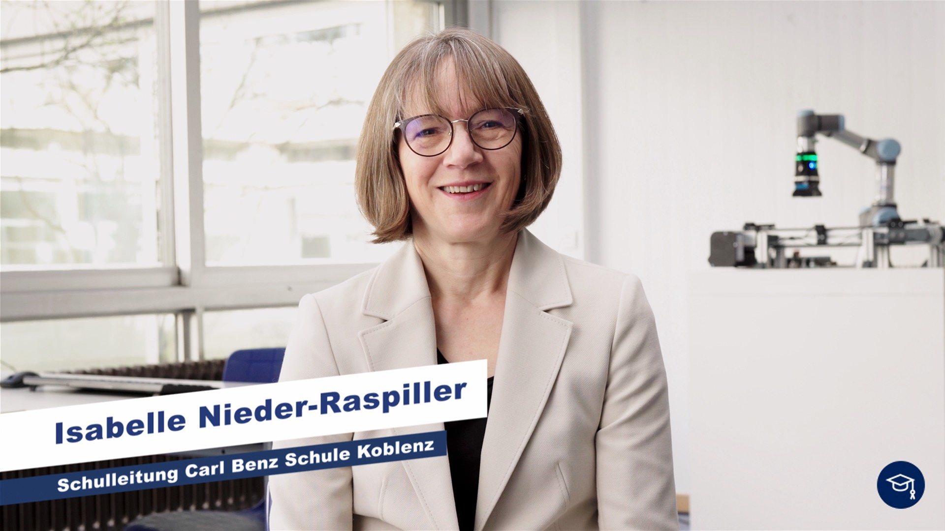 Die Schulleiterin sitzt in einem Klassenraum und wird interviewt.